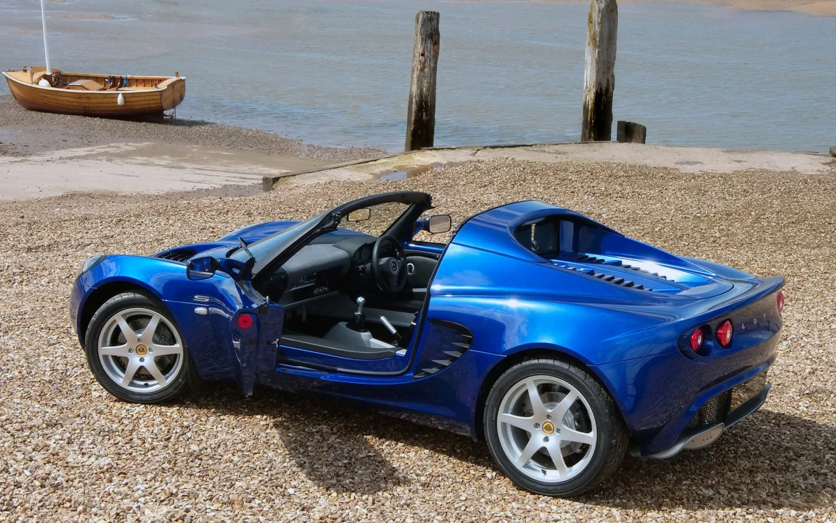 Синий Lotus Elise на галечном берегу у воды