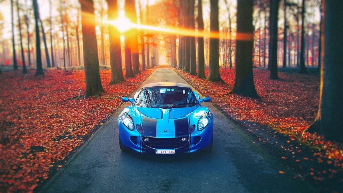 Синій Lotus Elise на тлі осінньої алеї у променях призахідного сонця