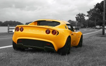 Ярко-желтый Lotus Elise на обочине дороги в пасмурный день