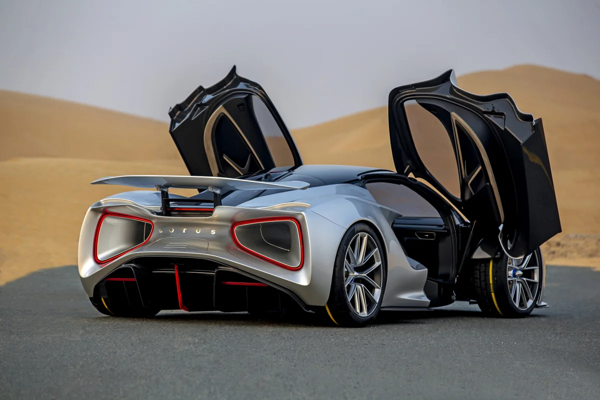 A silver Lotus Evija with its doors open against a backdrop of sand dunes