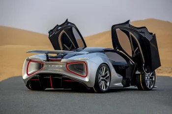 Серебристый Lotus Evija с открытыми дверями на фоне песчаных дюн
