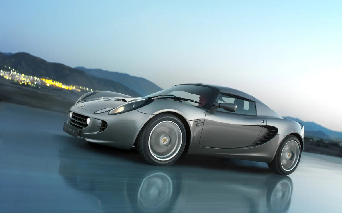 A silver Lotus Elise against the backdrop of the evening lights