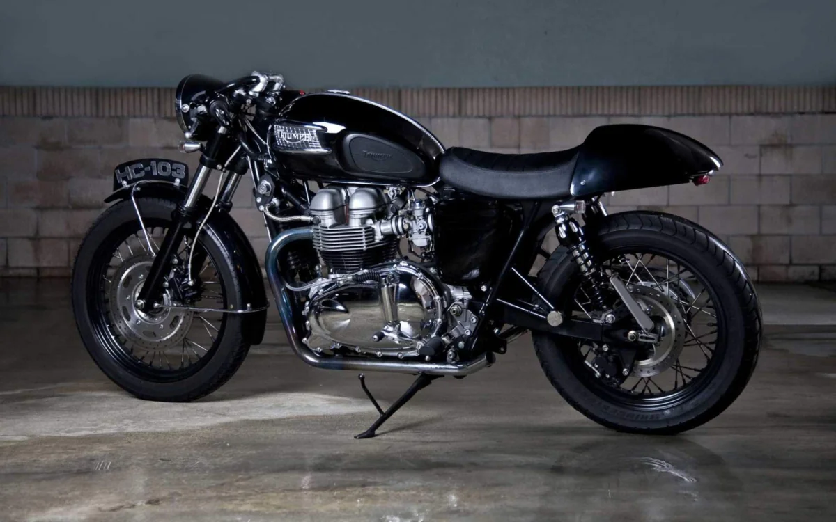 Черный кафе-рейсер Triumph Thruxton в полумраке гаража