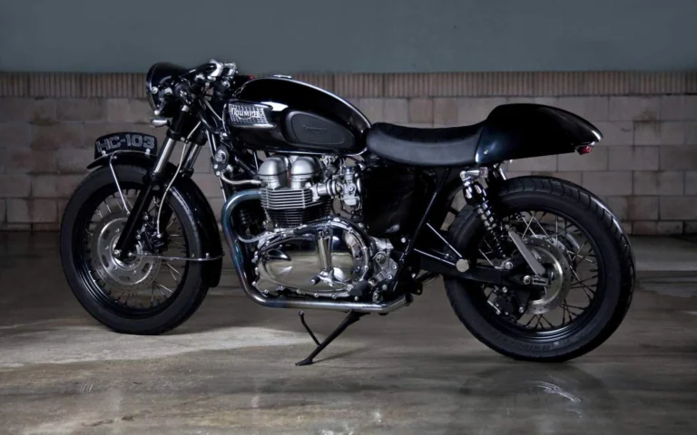 A black Triumph Thruxton café racer in the dim light of the garage